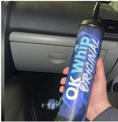 Hand holding an OK Whip Original charger tank inside a car interior.